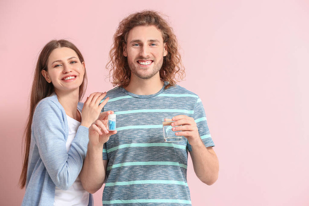 Junges Paar mit oralen Medikamenten gegen erektile Dysfunktion auf farbigem Hintergrund - Foto, Bild