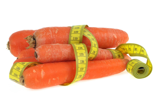 Zanahorias rodeadas por un metro de modista de cerca sobre un fondo blanco
 - Foto, imagen