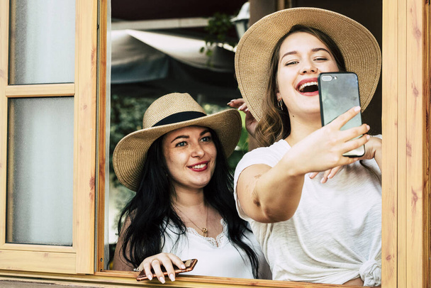 Pretty young curvy girls have lot of fun together in friendship taking selfie picture with modern big phone cellular to share on social media  - Photo, Image