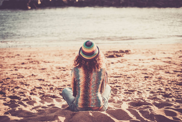 Soledad y meditación actividad de ocio al aire libre con vista trasera de la mujer de moda sentarse en la arena en la playa buscando y sintiendo la naturaleza y el océano
  - Foto, imagen