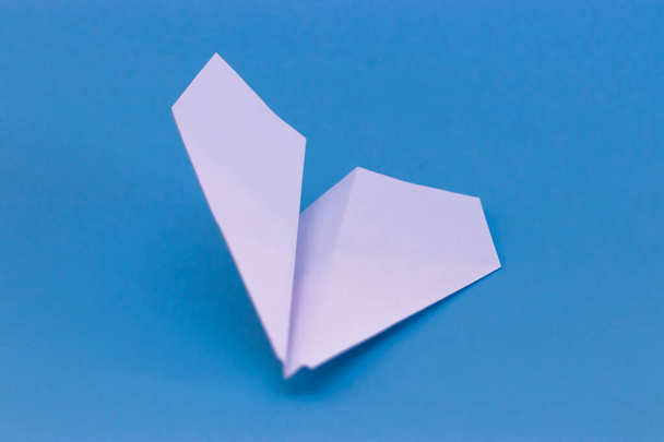 Beyaz kağıt uçağın düz yatağı ve pastel mavi arkaplan üzerine boş kağıt. - Fotoğraf, Görsel