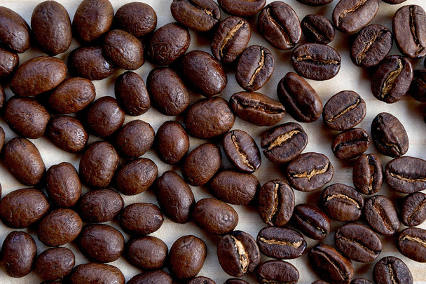 Granos de café derramados, oscuros, marrones, asados. Vista desde arriba.Montón de granos de café tostados brillantes de calidad
. - Foto, imagen
