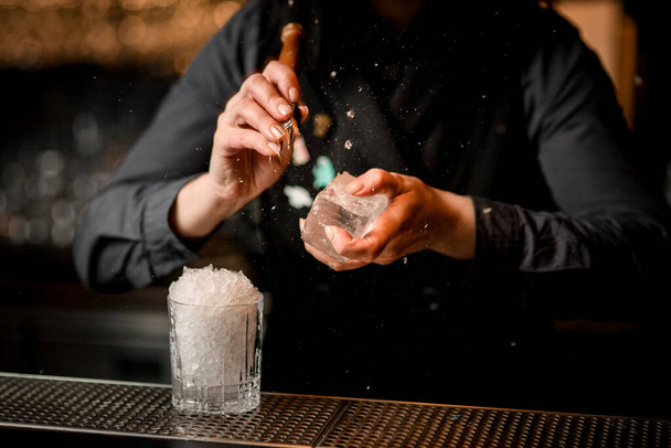 Kadın barmen büyük bir buz parçasını özel bir aletle kırıyor.. - Fotoğraf, Görsel