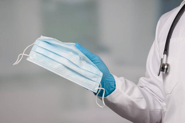 close-up van de hand van de arts in medische handschoenen toont medisch gezichtsmasker voor bescherming tegen infectie  - Foto, afbeelding