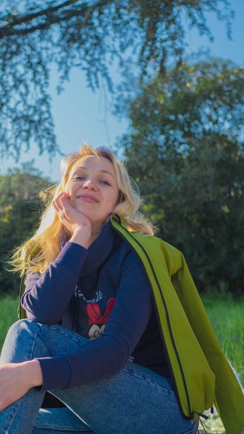 portret młodej blondynki w naturze w zielonej kurtce. - Zdjęcie, obraz