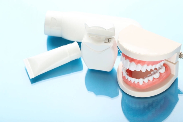 Modello di denti con bottiglie e filo dentale su sfondo blu
 - Foto, immagini