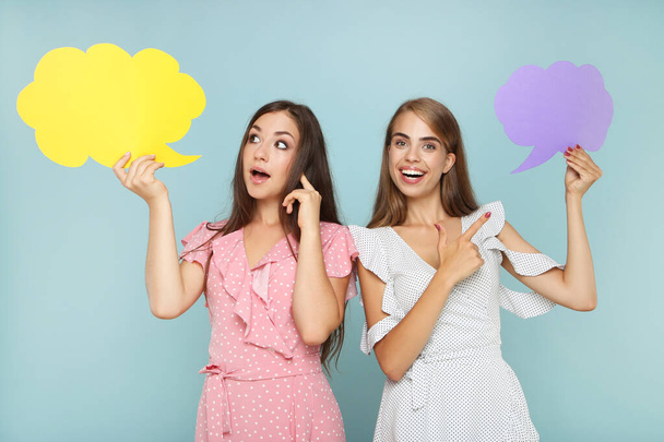 Young happy girlfriends with paper speech bubbles on grey background - Foto, afbeelding