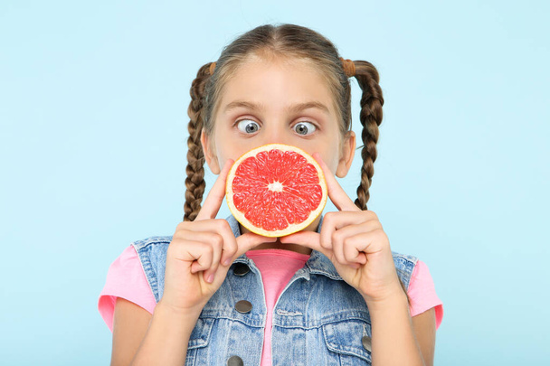 Молодая девушка с грейпфрутом на синем фоне
 - Фото, изображение