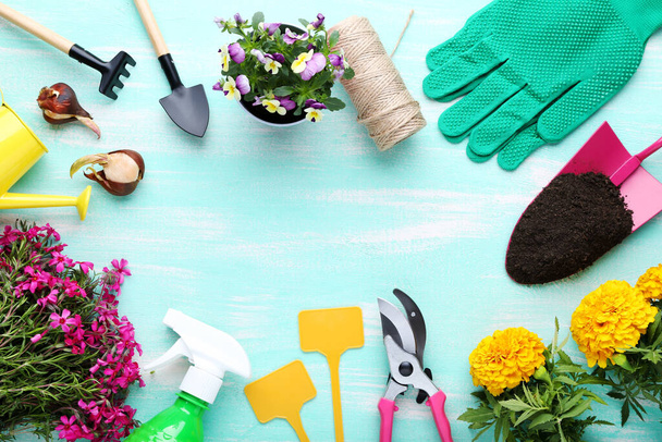 Different garden tools with flowers on mint wooden table - Zdjęcie, obraz