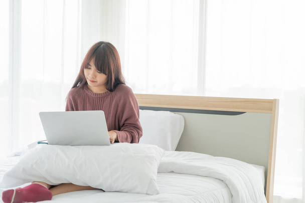 Asian women working with laptop on bed at home - Foto, afbeelding
