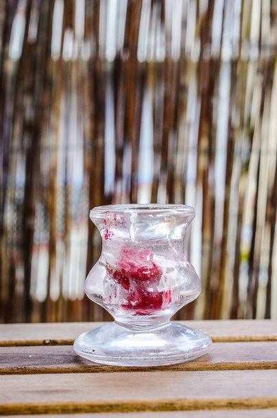 A vertical shot of a glass candle holder on a wooden surface - Foto, afbeelding