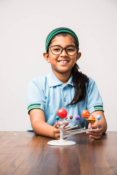 Indian Schoolgirl / girl child studying Planets or planetary science with 3d Model of our solar system - Photo, Image