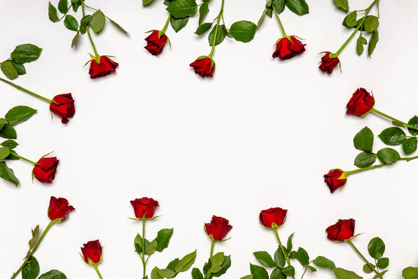 Frame made of fresh red roses flowers on white background. Beautiful floral composition, greeting card for holiday. Flat lay, top view, space for text, mock up. - Foto, Imagem