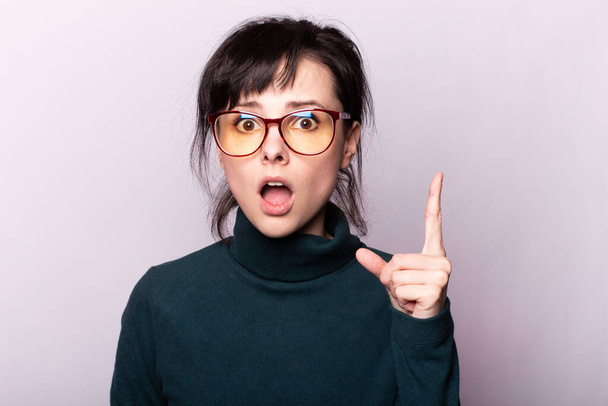 girl in a green turtleneck, glasses, portrait on a gray background - Photo, Image