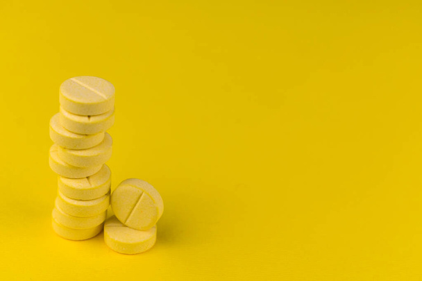 Vitamine C tabletten in een stapel op een gele achtergrond. Kopieerruimte. - Foto, afbeelding