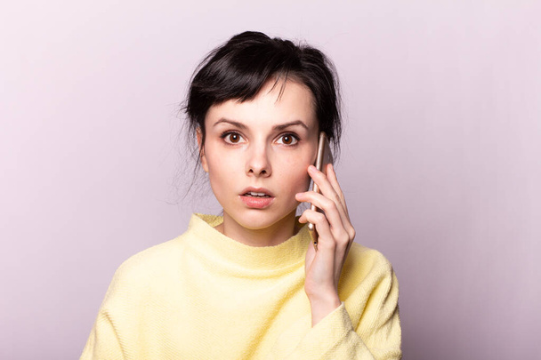 beautiful girl in a yellow sweater speaks on the phone - Zdjęcie, obraz