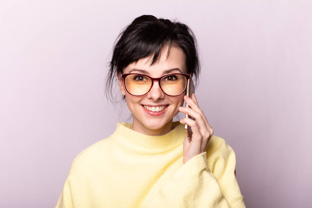 beautiful girl in yellow sweater glasses speaks on the phone - Photo, image
