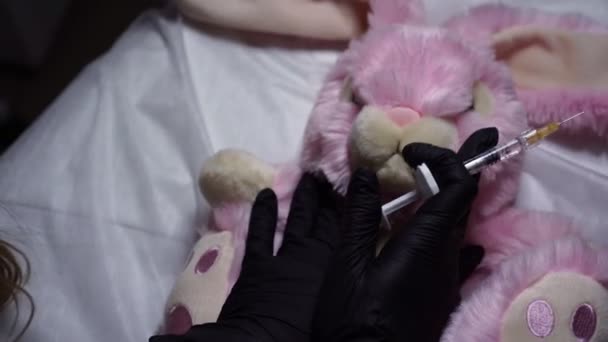 Um coelho de brinquedo mole recebe uma injeção com uma seringa. Conceito de cosmetologia, cuidados com a pele
. - Filmagem, Vídeo