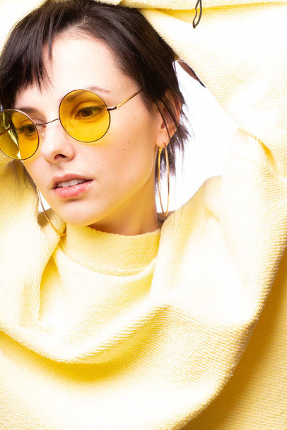 beautiful girl in yellow glasses and a yellow sweater - Foto, afbeelding