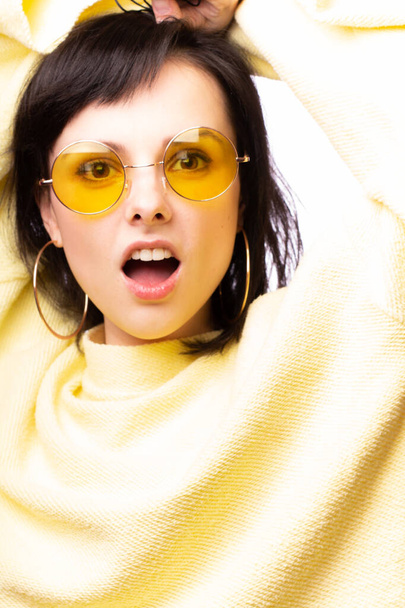 mooi meisje in gele bril en een gele trui - Foto, afbeelding