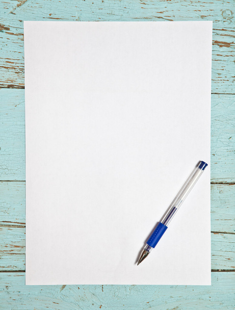 Sheet of white paper and a pen on a wooden background - Foto, imagen