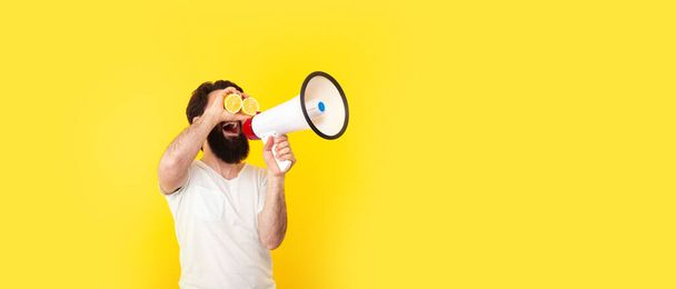 positive bearded man with megaphone over yellow background, concept of summer mood, panoramic mock-up with space for text - Photo, Image