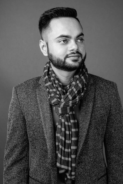 Studio shot of young bearded Indian man against gray background in black and white - Foto, Imagen