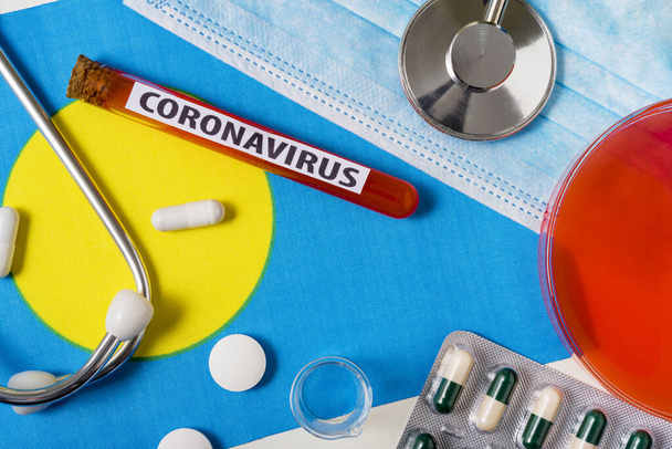 Coronavirus, nCoV-Konzept. Atemschutzmaske, Stethoskop, Spritze und Pillen auf der Flagge Palaus sind von oben zu sehen. Ein neuer Ausbruch des chinesischen Coronavirus - Foto, Bild