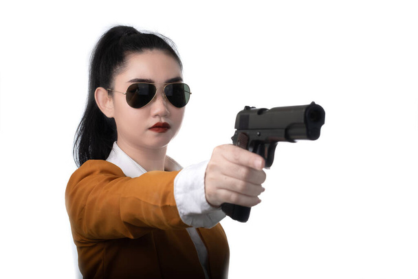 Портрет красива жінка в жовтому костюмі одна рука тримає пістолет на білому тлі, молода сексуальна дівчина довге волосся з пістолетом дивиться на камеру, гарненькі жінки стоять з пістолетом
 - Фото, зображення