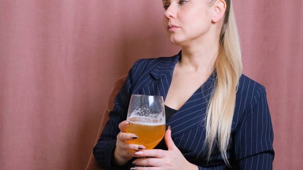 Female alcoholism for young blond woman holding bubbly wine, beer. Woman relaxing after work by drinking wine in the kitchen - Photo, Image