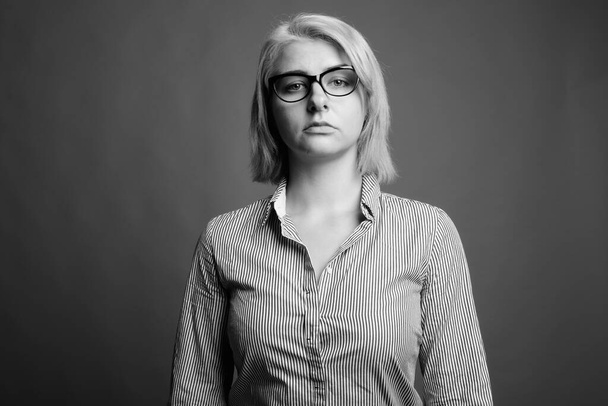 Studio shot van jonge mooie zakenvrouw met kort haar tegen grijze achtergrond in zwart-wit - Foto, afbeelding