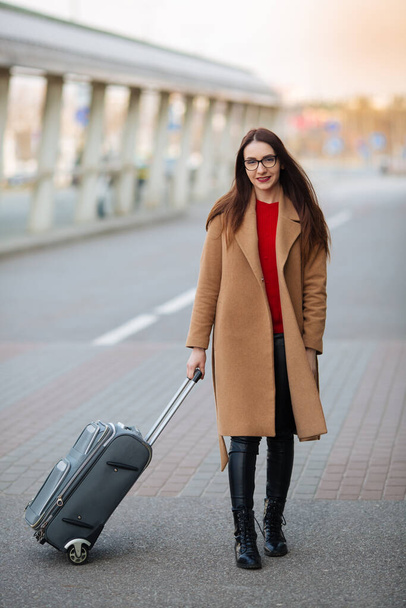Travel, business trip. People and technology concept - happy young woman with travel bag on city street. - Foto, afbeelding