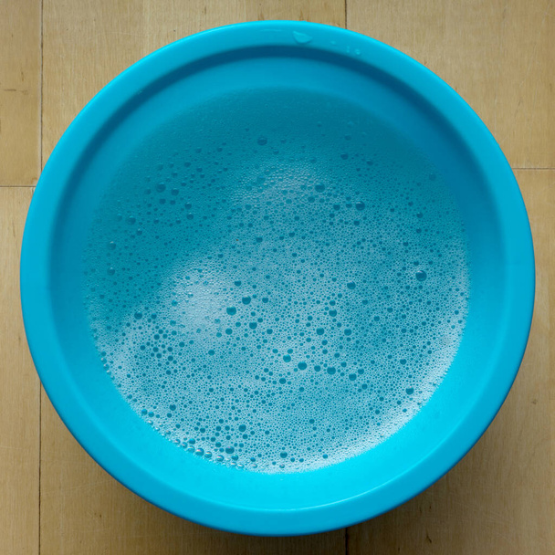 Blaue Schüssel mit Seifenwasser und Schaum - Foto, Bild