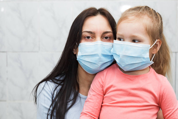 Quarantined woman and baby girl wearing medical masks. Baby in the focus. - 写真・画像
