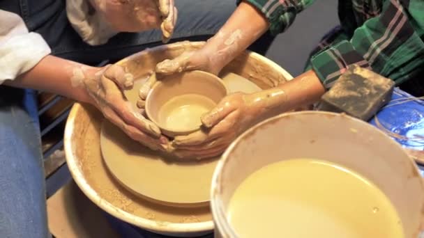 Jongen en vrouw werkt met aardewerk wiel in een workshop, slow motion - Video