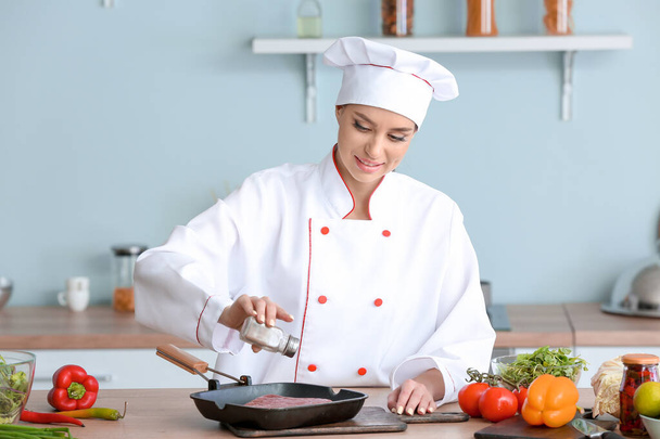 Female chef cooking meat in kitchen - Fotó, kép