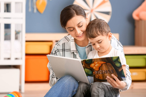 Täti ja söpö pieni poika lukeminen kirja kotona
 - Valokuva, kuva