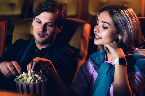 Caucasian lover enjoying to watch movie and eating popcorn together in the cinema - Фото, изображение