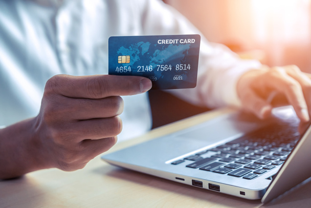 Junge Mann verwenden Kreditkarte für Online-Einkäufe Zahlung auf Laptop-Computer-Anwendung oder Website. E-Commerce und Online-Shopping-Konzept. - Foto, Bild
