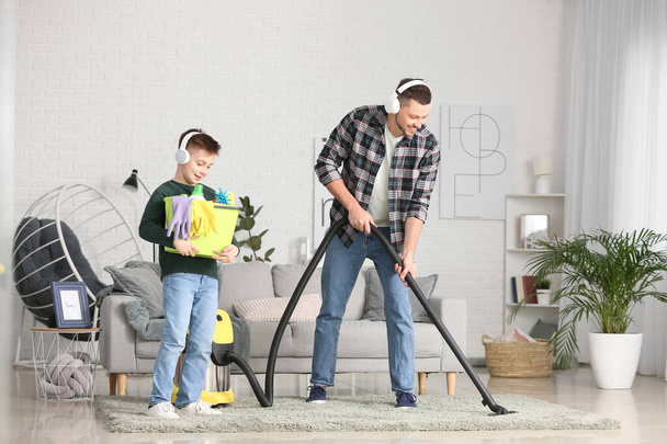Little boy and his father hoovering floor in room - Foto, immagini