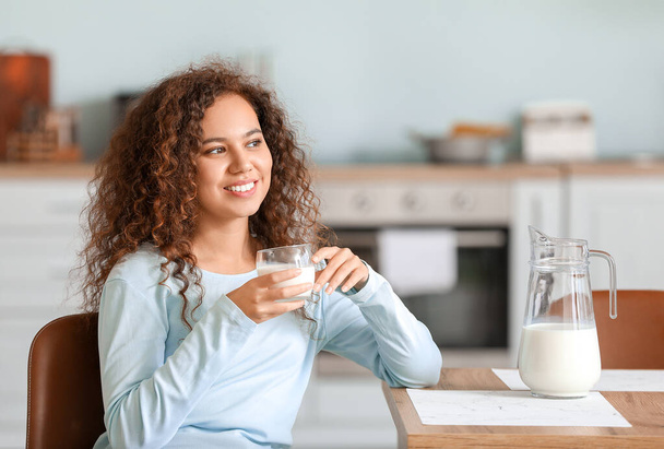 Young African-American woman with milk in kitchen - Photo, Image