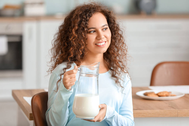 Jovem afro-americana com leite na cozinha
 - Foto, Imagem