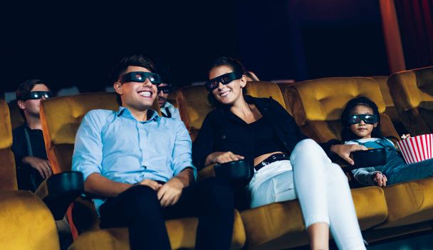 Group of people watch movie with 3D glasses in cinema theater with interest looking at the screen, exciting and eating popcorn - Foto, afbeelding
