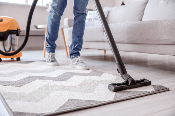 Young man hoovering floor at home - Photo, image