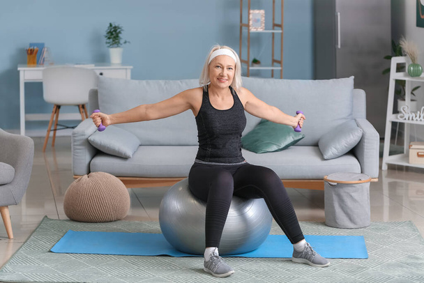Sportovní starší žena dělá cvičení s fitness míč doma - Fotografie, Obrázek