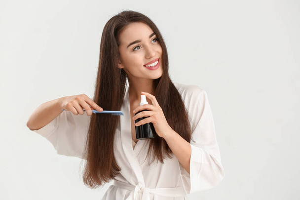 Schöne junge Frau mit Kosmetik für Haare auf weißem Hintergrund - Foto, Bild
