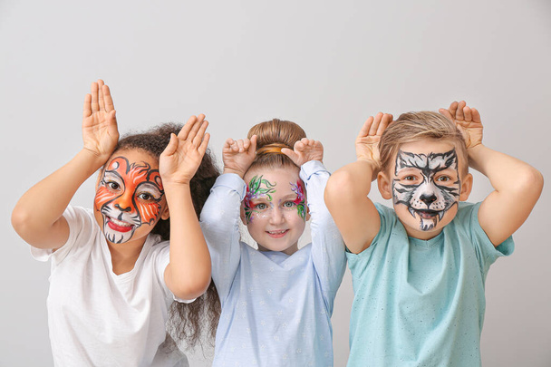 Funny children with face painting on light background - Φωτογραφία, εικόνα
