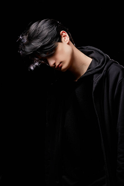 dramatic portrait of a young man in black clothes on a black background - Photo, Image