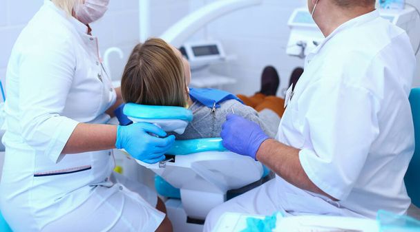Senior male dentist in dental office talking with female patient and preparing for treatment - Photo, Image