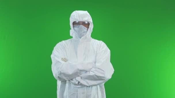 video portrait of a man in a protective suit who is standing on a green background with his hands folded across his chest - Video